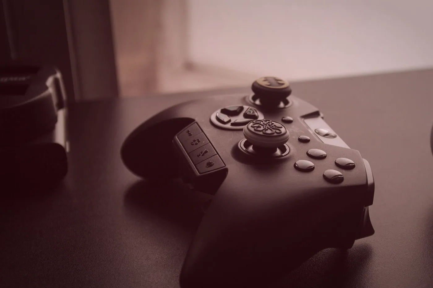 The console corner of the club room, with a deep sofa, a large screen and two controllers resting on a cushion